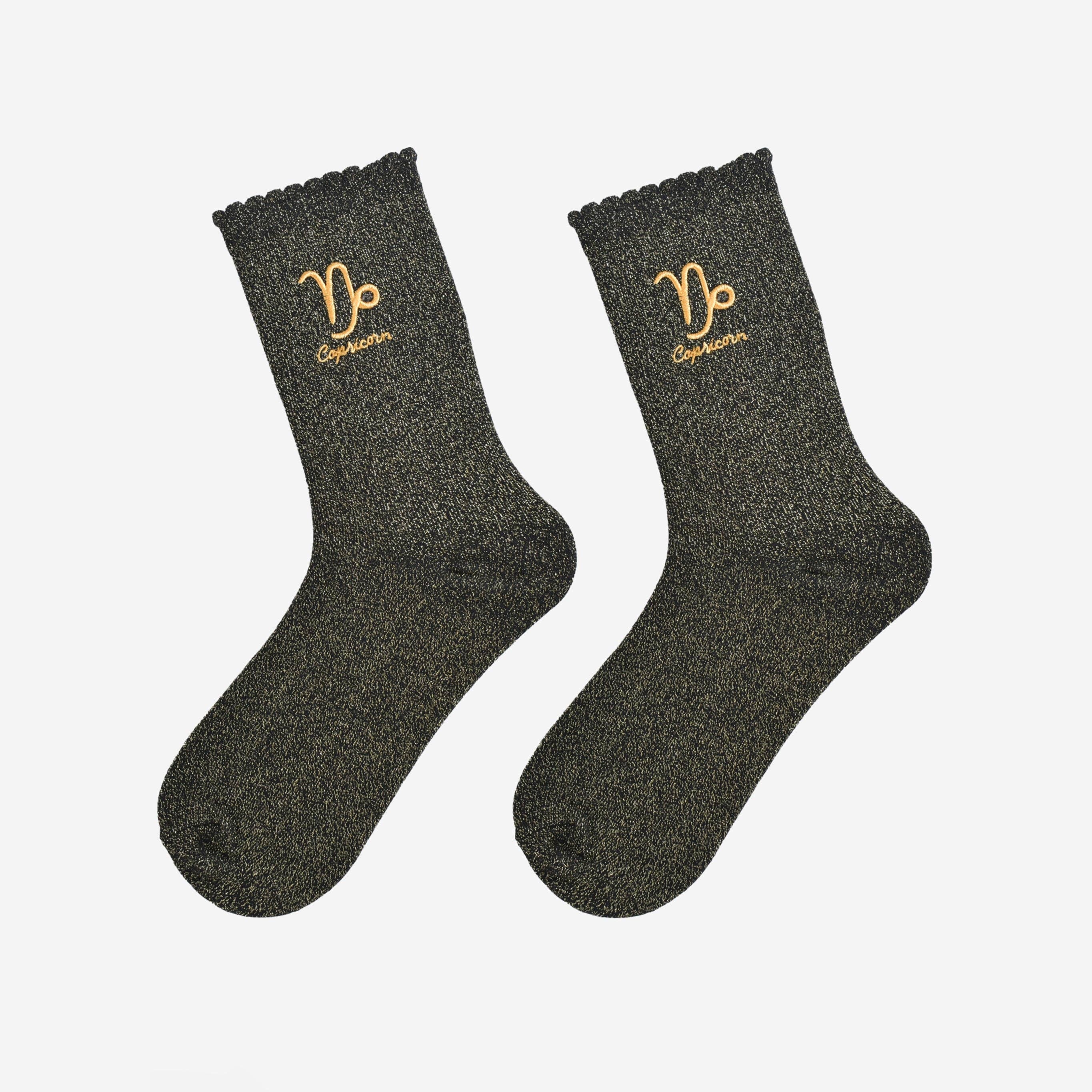 Pair of dark gray socks with gold zodiac symbols on a light gray background