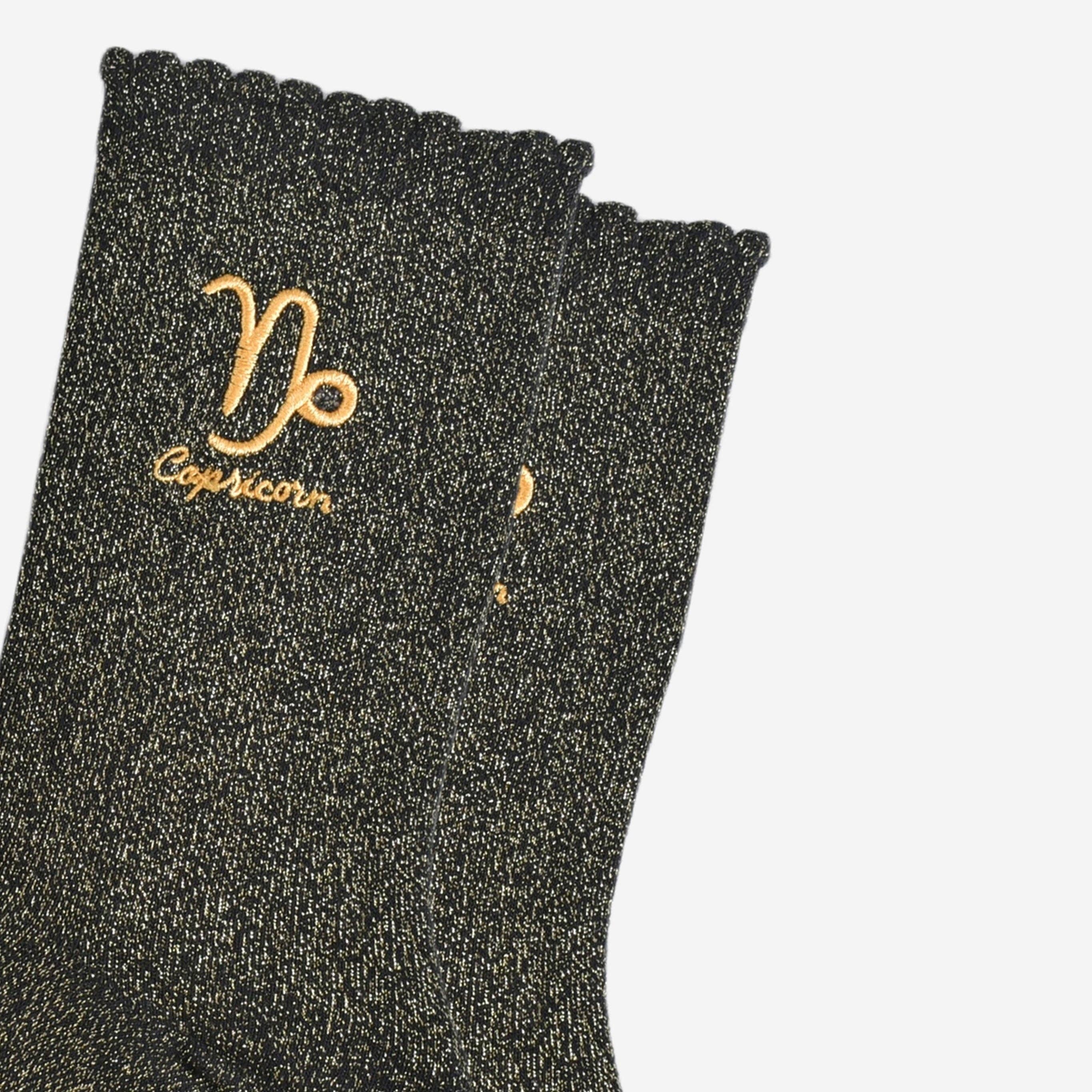 Black glittery sock with Capricorn symbol and text on a white background