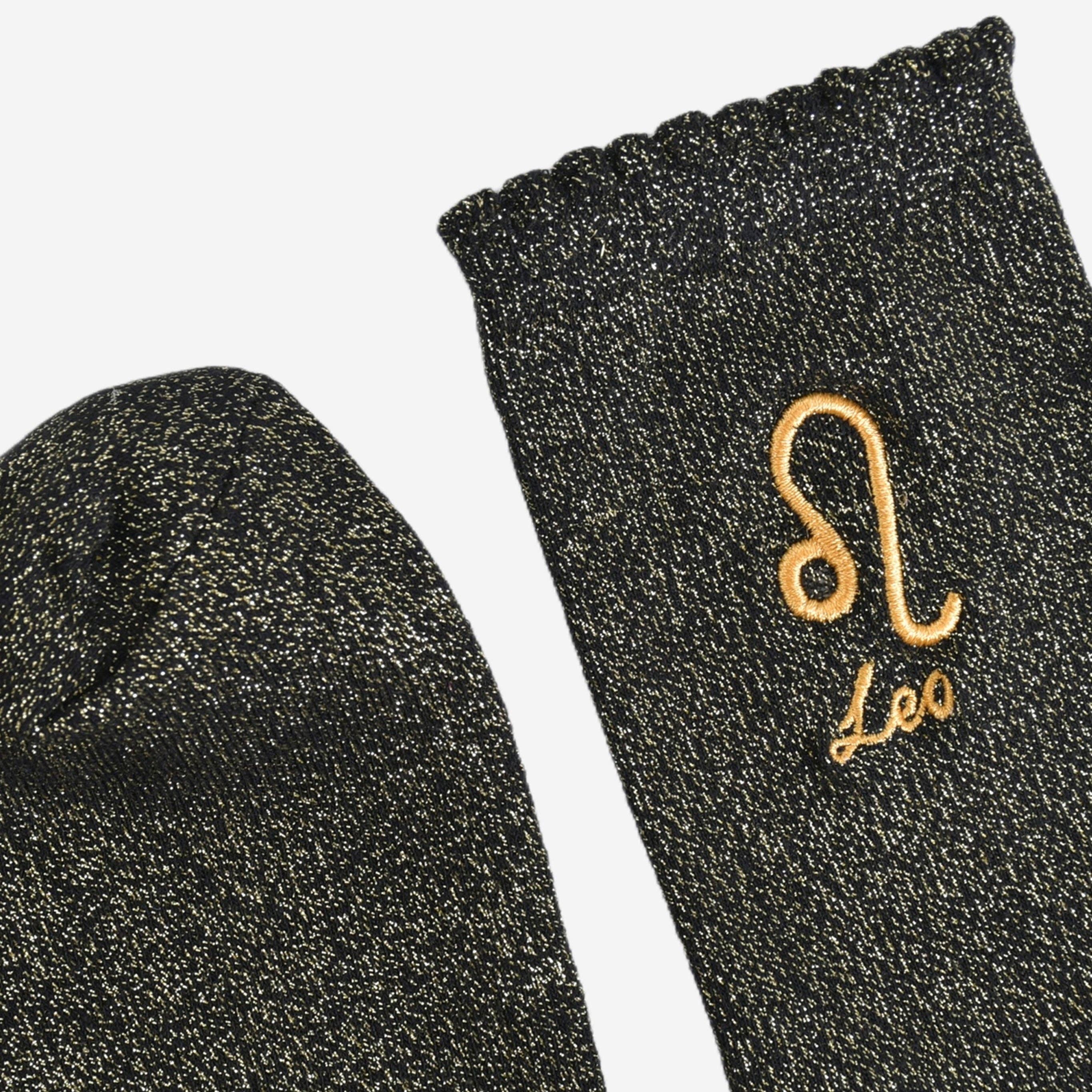 Black socks with gold embroidered 'Leo' design on a white background