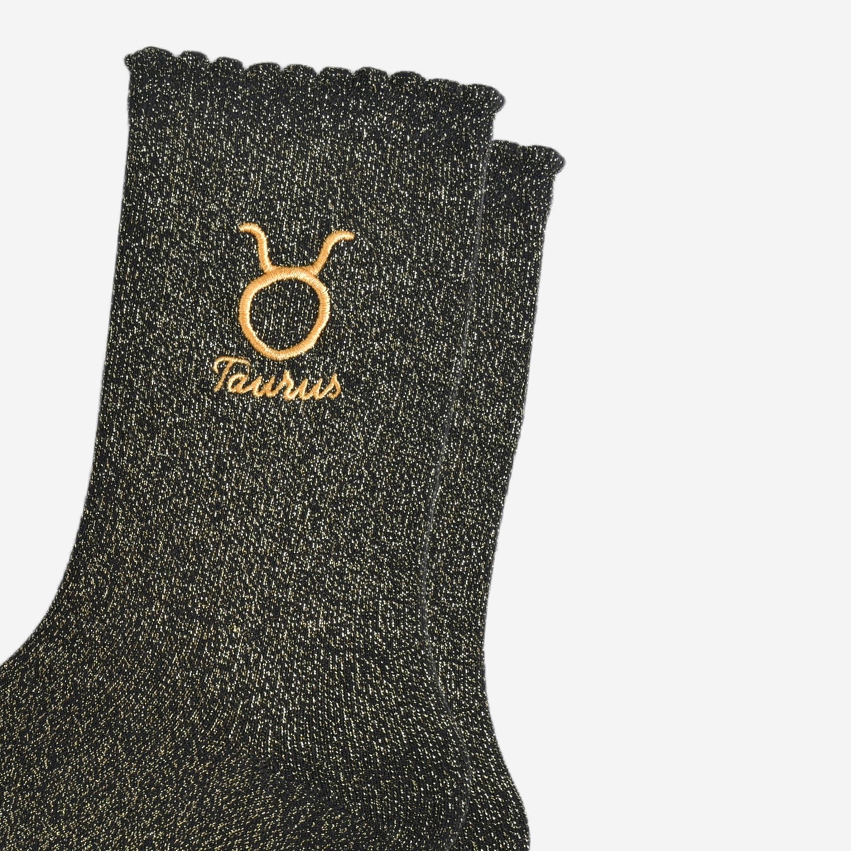Black glittery sock with Taurus zodiac sign embroidery on a white background