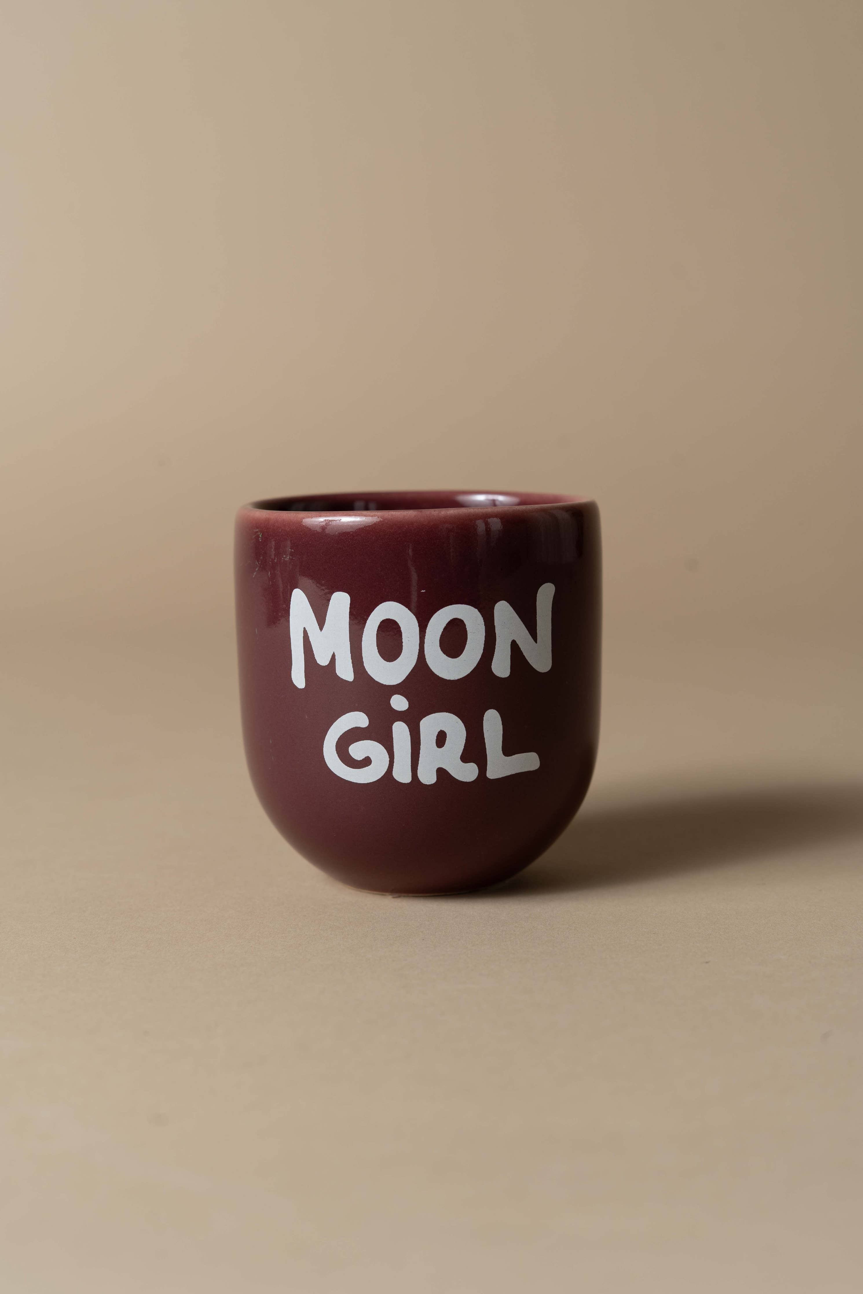 Brown ceramic mug with 'MOON GIRL' text on a beige background