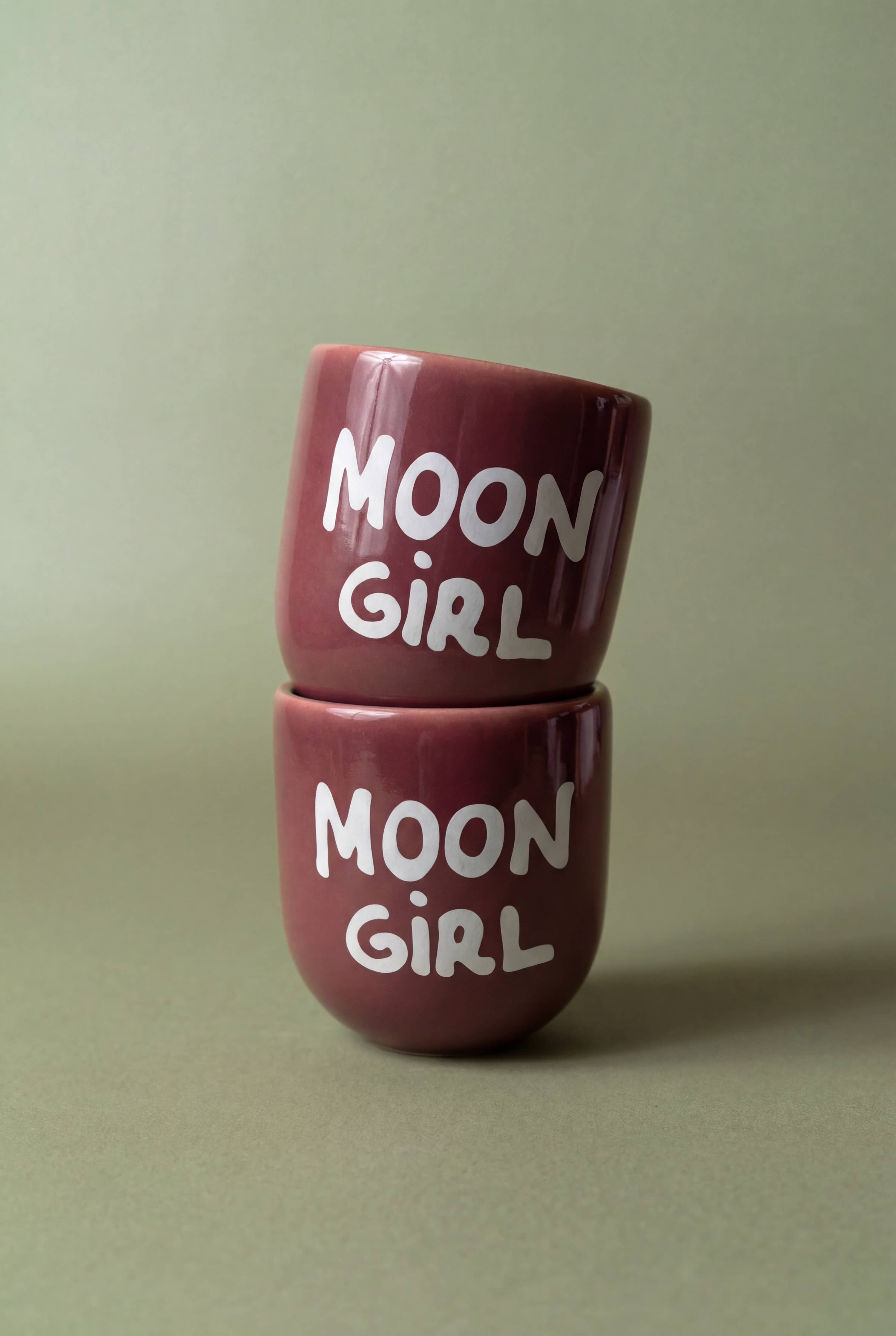 Two maroon cups with 'MOON GIRL' text on a beige background