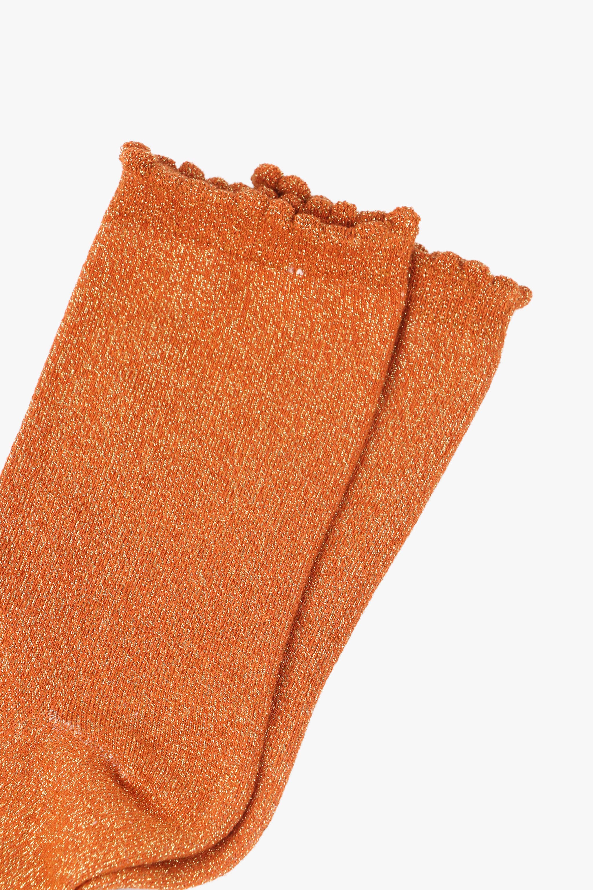 Pair of orange glittery socks on a white background