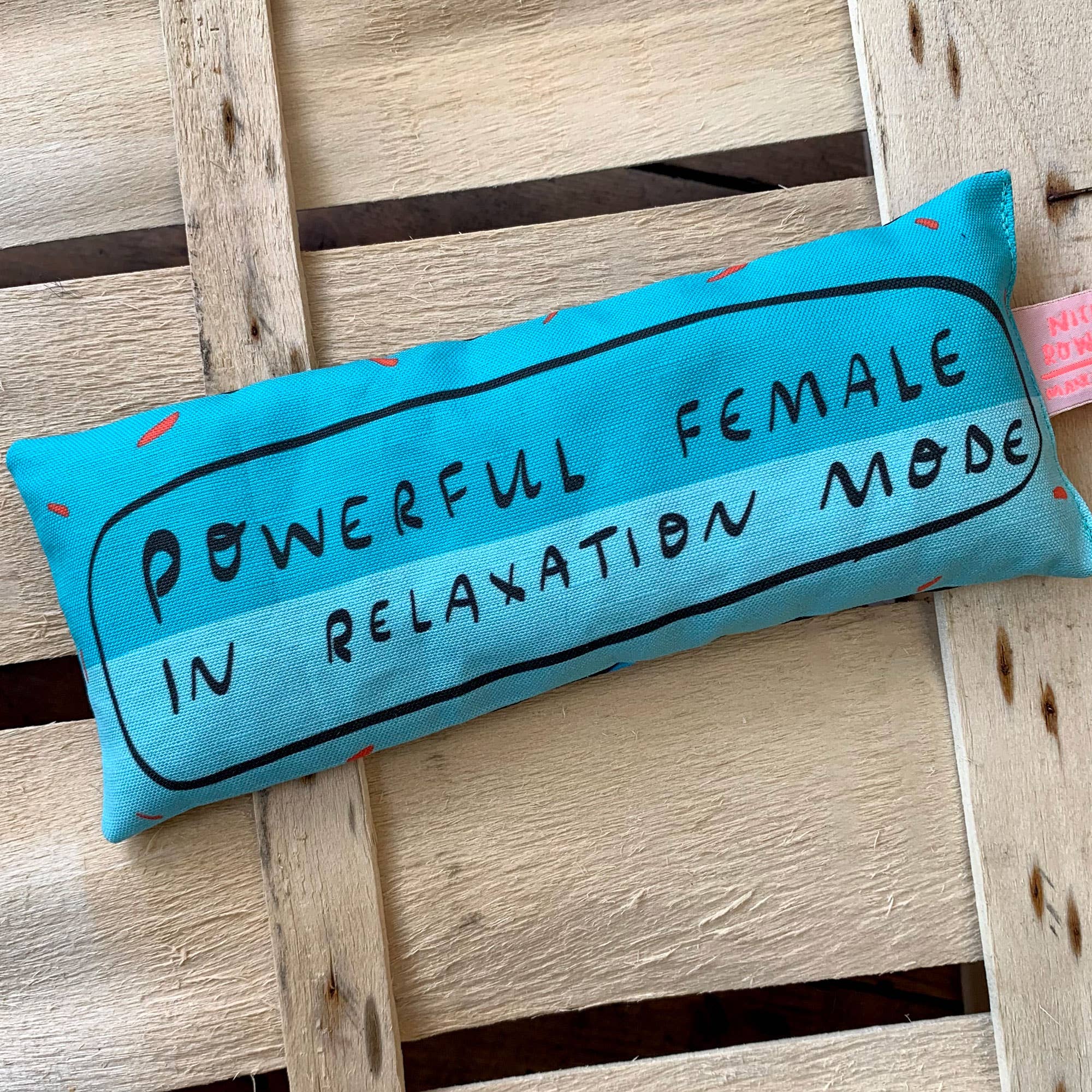 a blue eye bag with the words "powerful female in relaxation mode" on a wooden backdrop