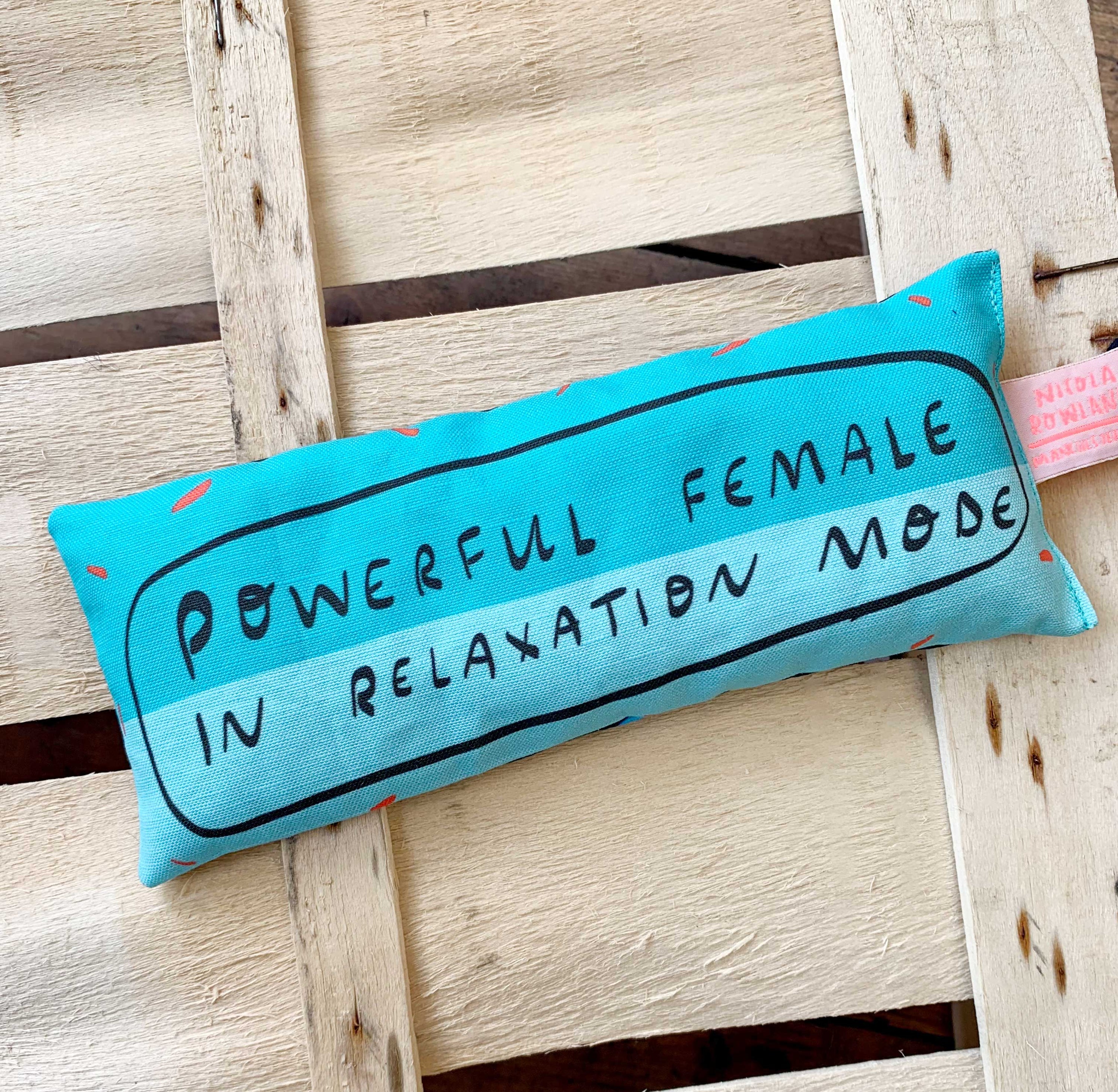 Turquoise eye pillow with text on a wooden background