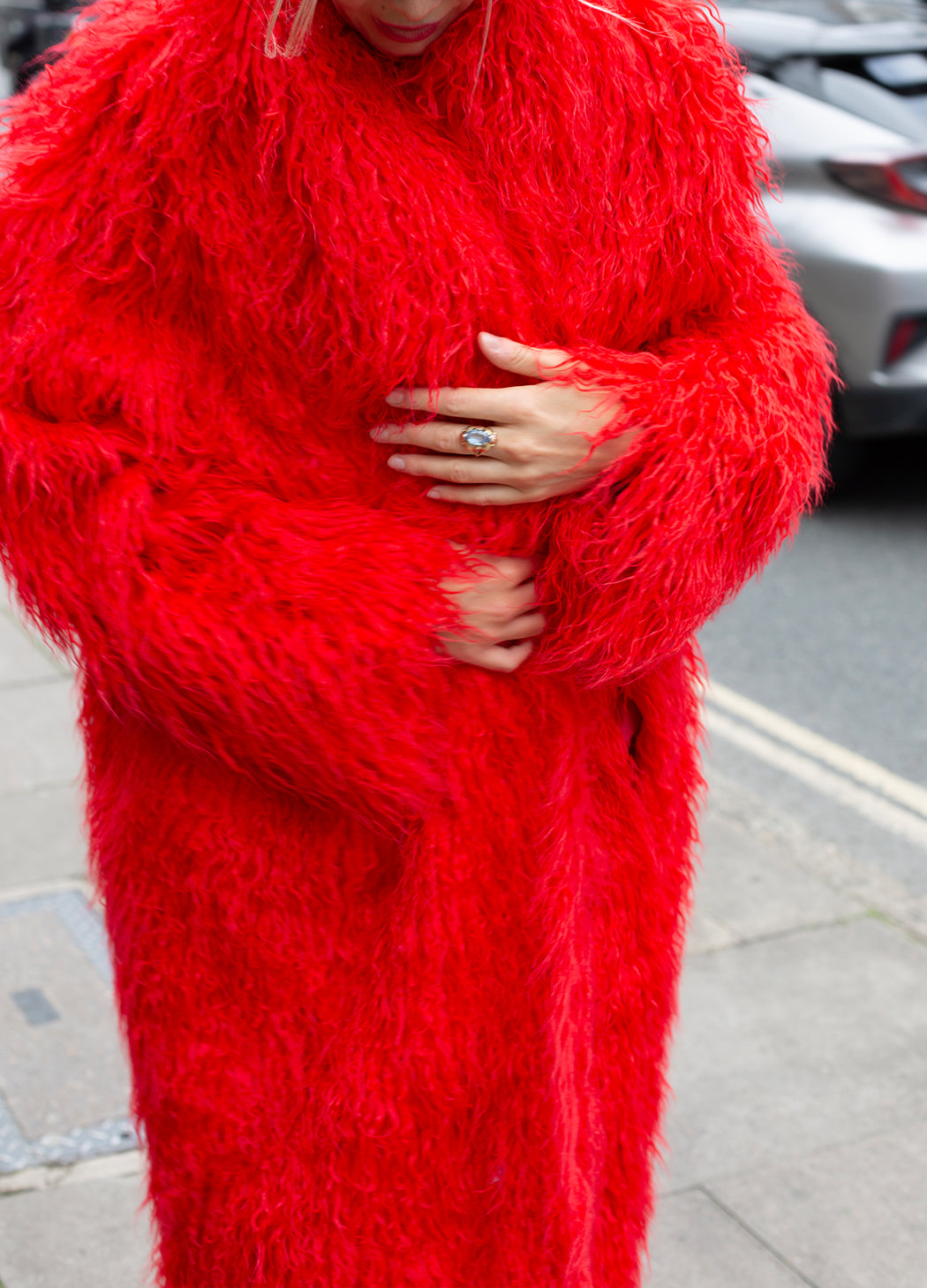 Person wearing a bright red, fluffy outfit on a street.