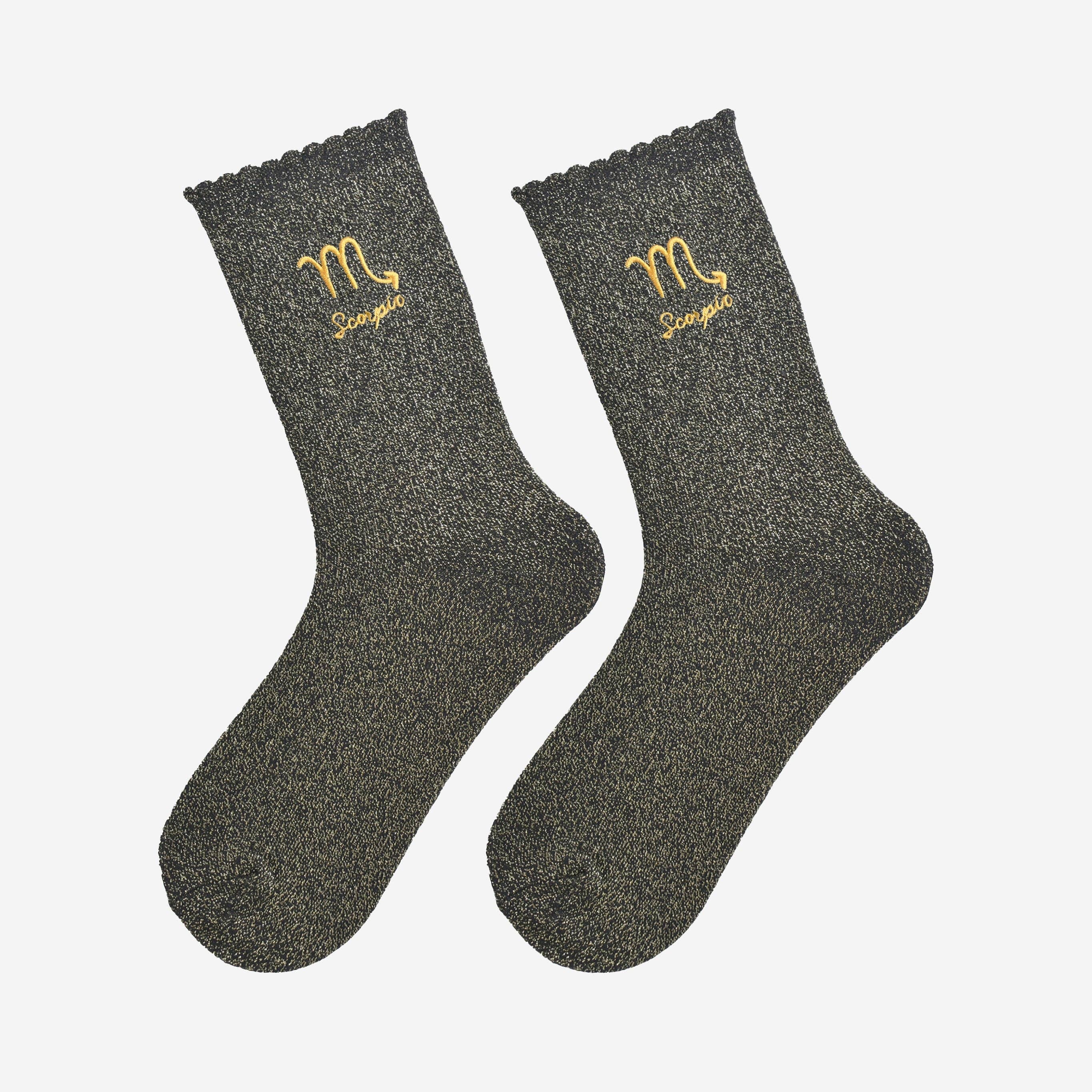 Pair of dark glitter gray socks with Scorpio zodiac sign embroidery on a white background