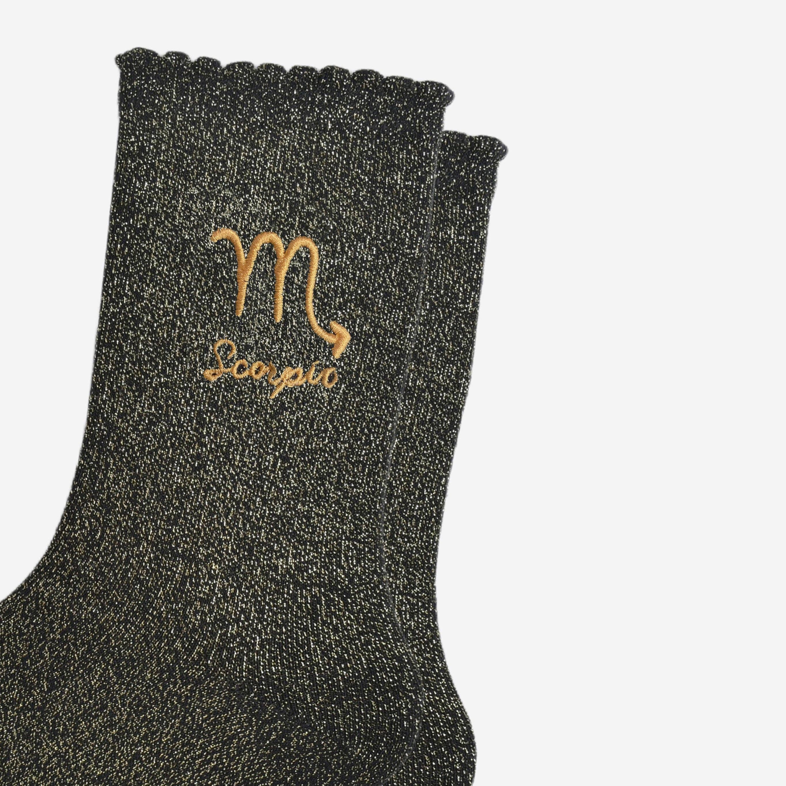 Black glittery sock with Scorpio symbol and text on a white background