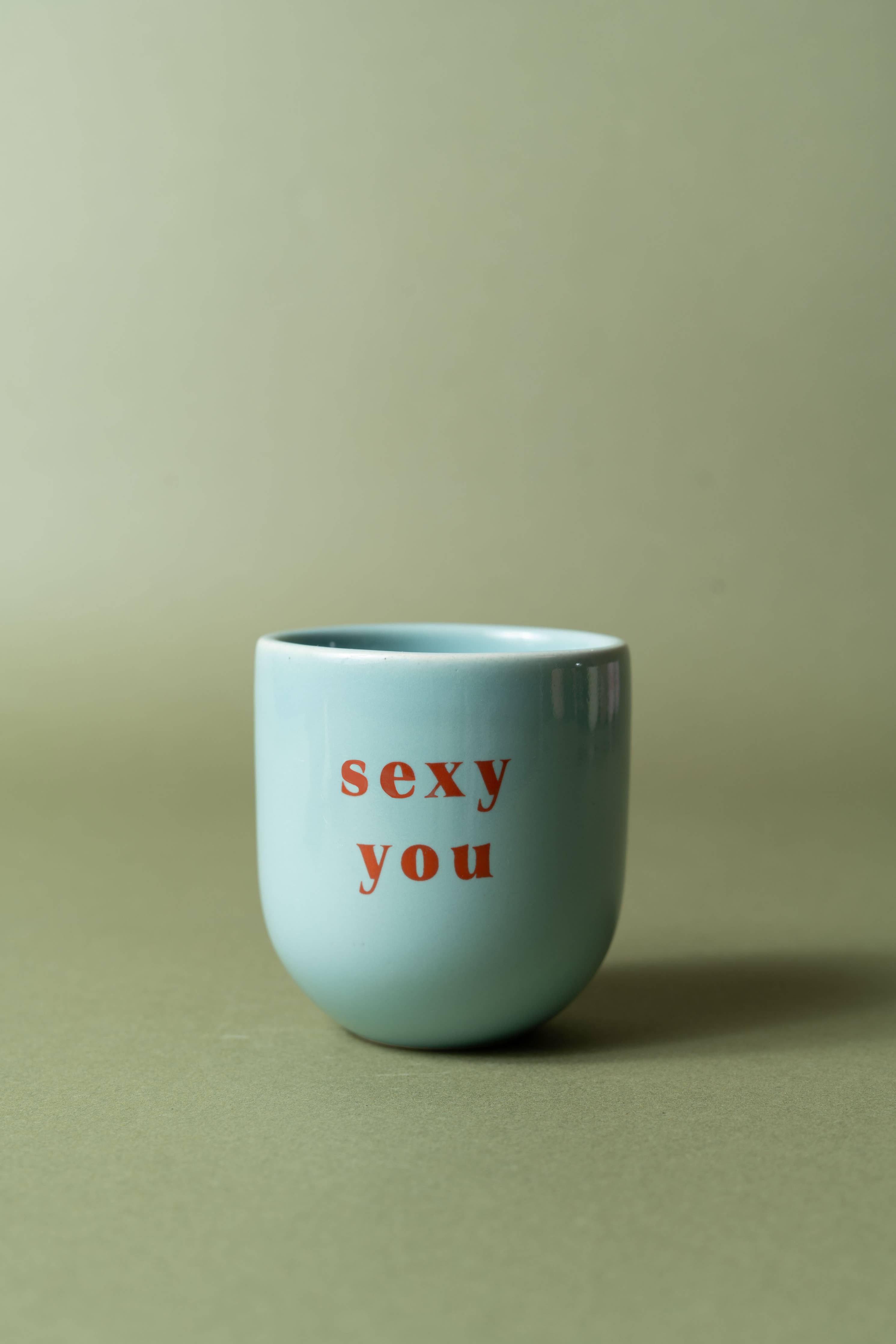 Light blue mug with red text 'sexy you' on a green background