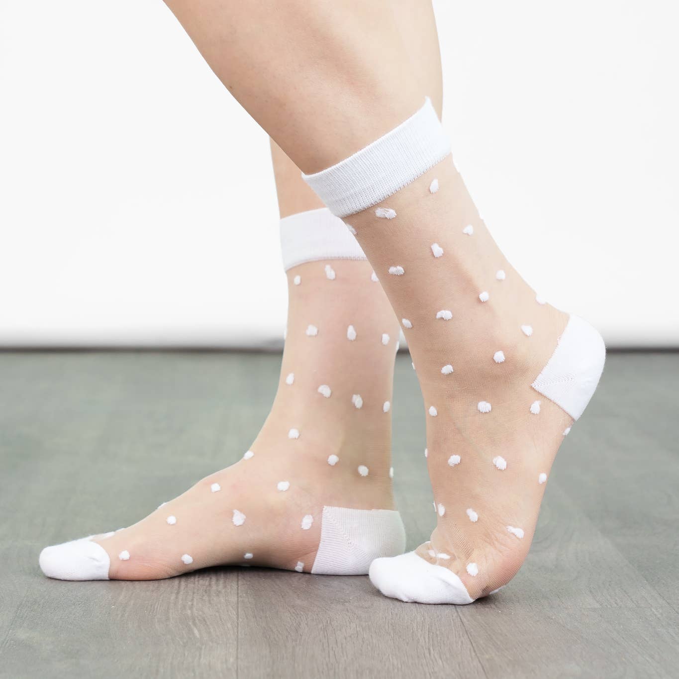 Sheer socks with white polka dots and white ankle socks on a neutral background