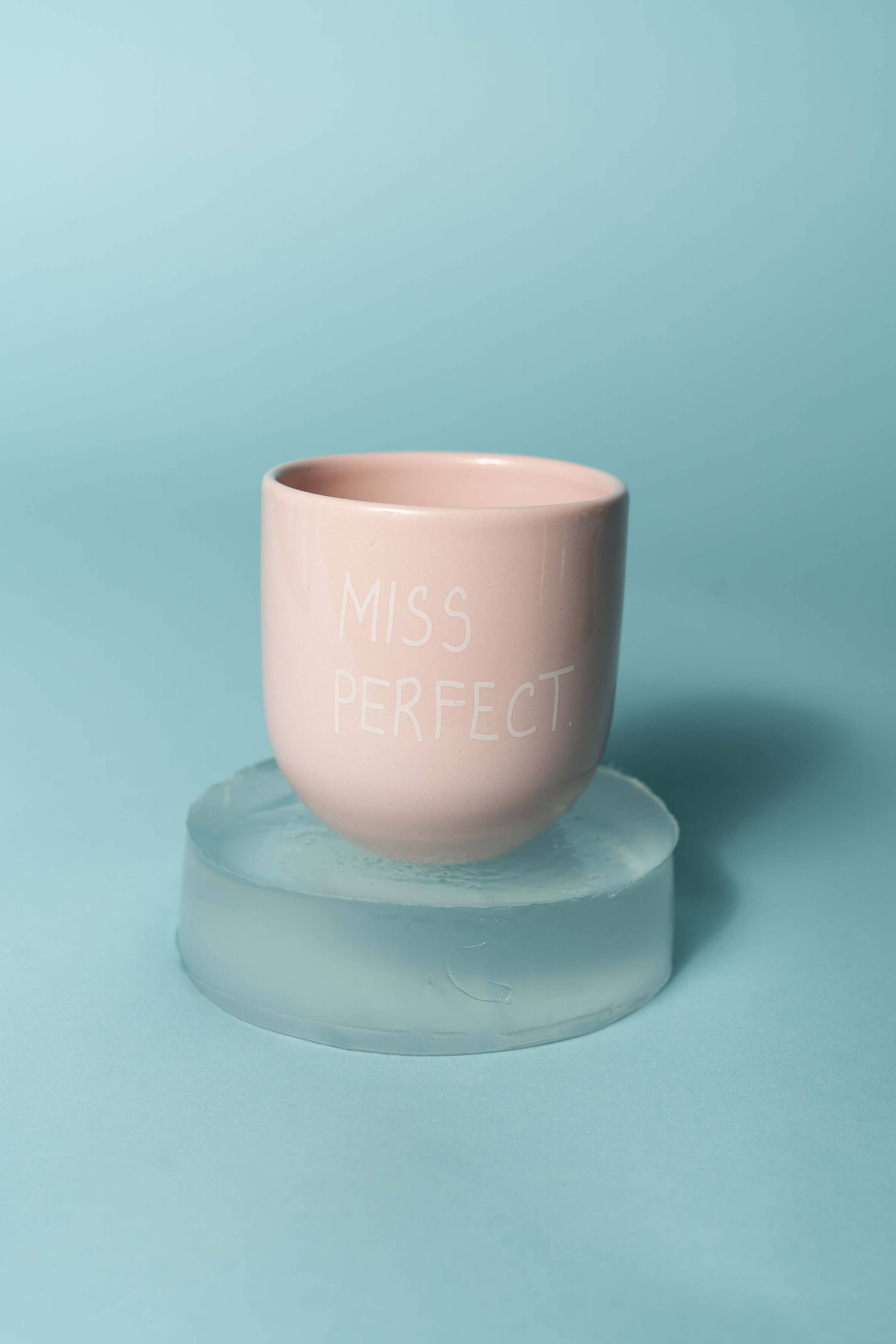 Pink cup with 'Miss Perfect' text on a light blue background