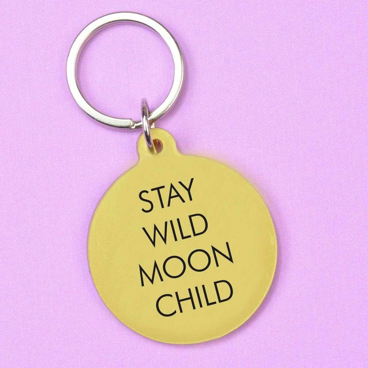 Gold keychain with 'Stay Wild Moon Child' text on a pink background