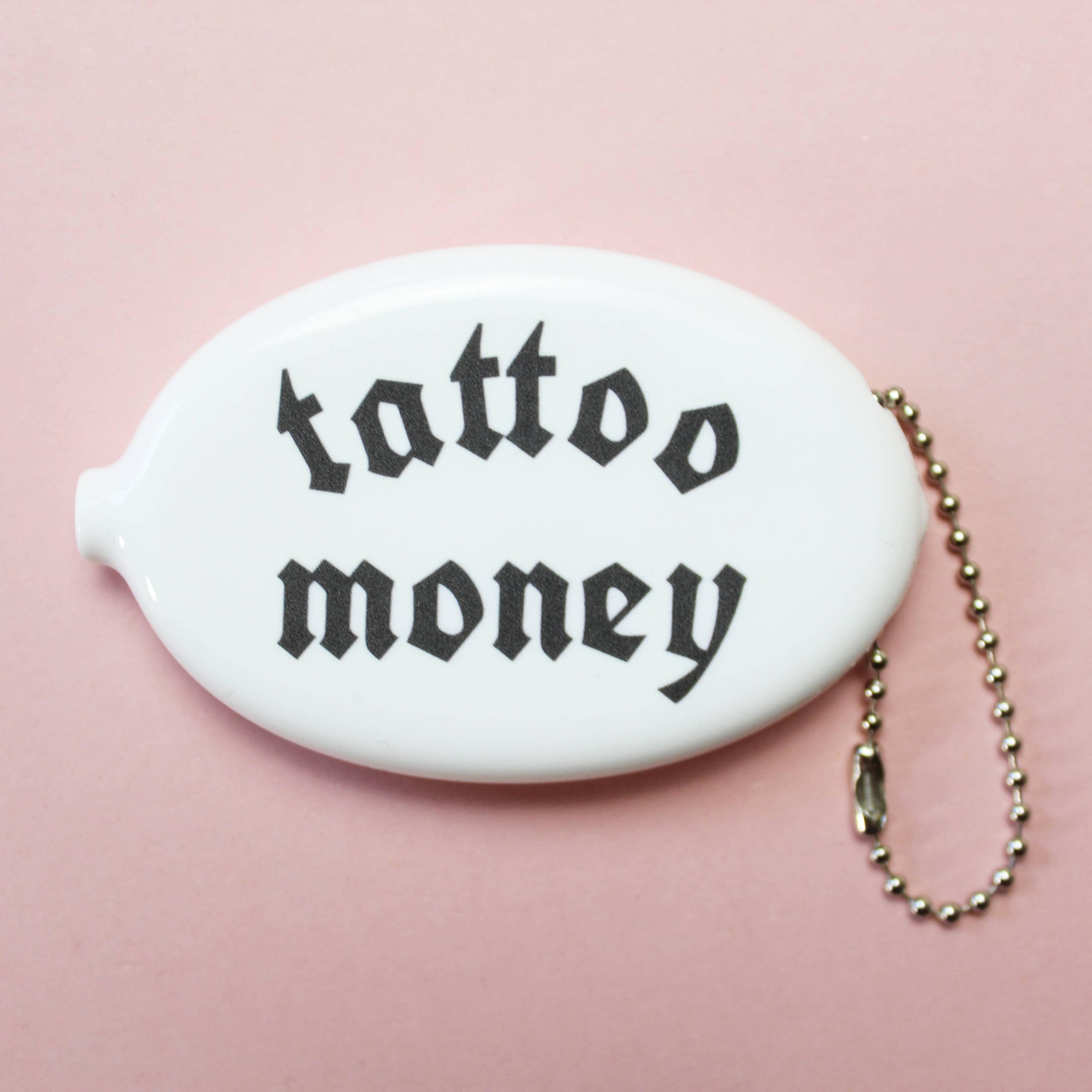 White pouch with 'tattoo money' text on a pink background