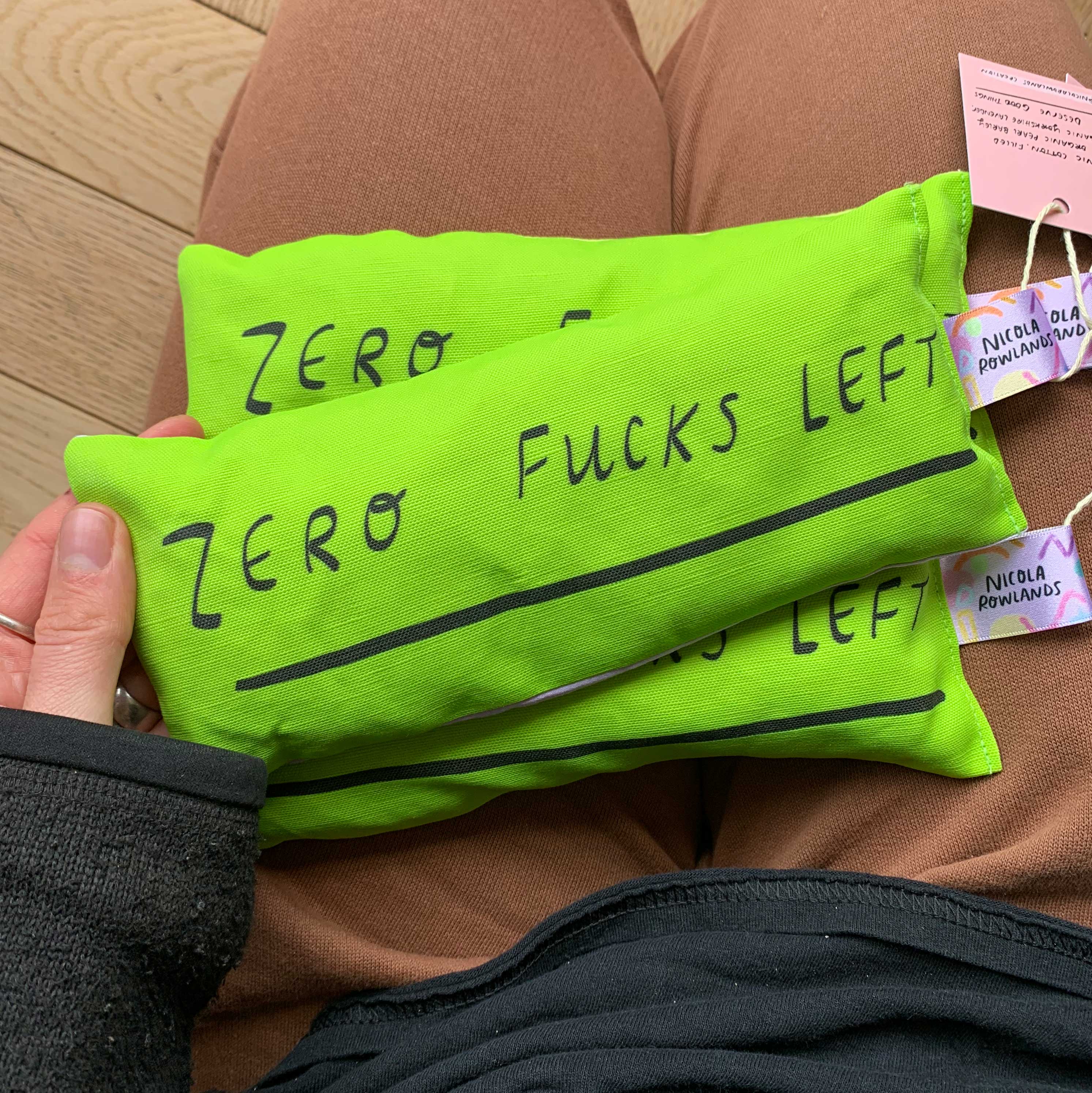 a green zero fucks left eye bag organic and handmade on someones lap
